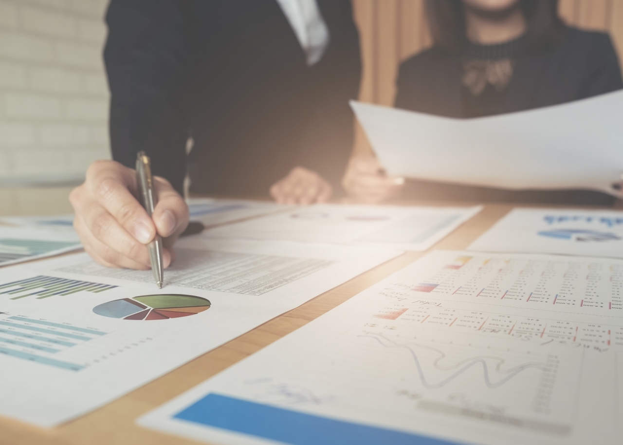 business consulting or finance budget plan, business advisor holding pen pointing to explain method profit with business owner use pen write to notebook and use laptop computer